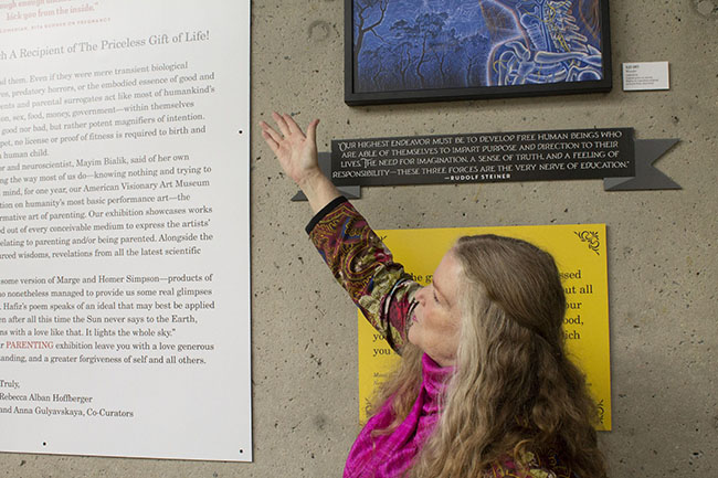 A blonde woman gestures to text on a museum wall