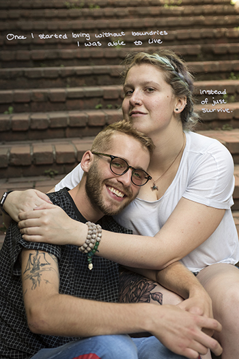 A man and woman sitting and hugging while facing camera and smiling