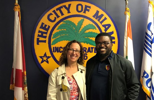 Man and woman standing in front of the City of Miami logo 