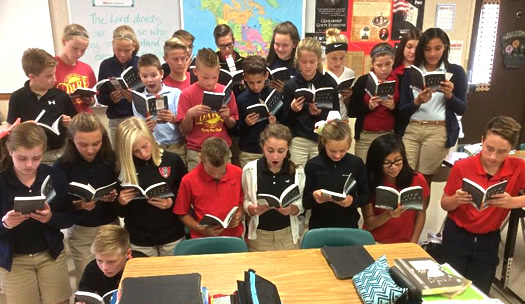 Three rows of students reading paperback copies of FIve Skies in front of the teahers desk 