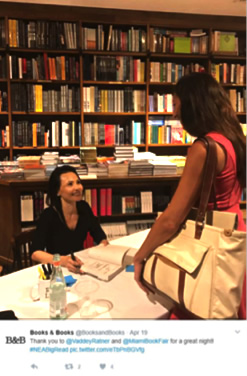 screencap from Twitter. Author Vaddey Ratner signs book for young Big Read participant in a bookstore. 