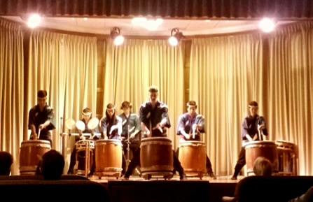 Seven taiko drummers perform on stage