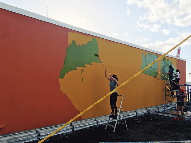 Teenage students paint an outdoor mural