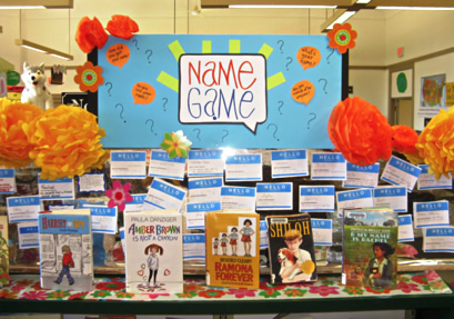  A library display in front of a Name Game poster featuring books and other items on the theme of names and genealogy