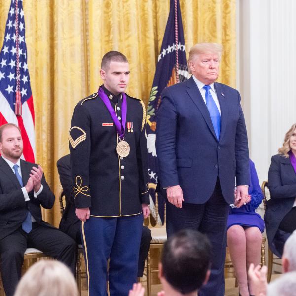 Man in uniform standing next to man in suit at ceremony. 