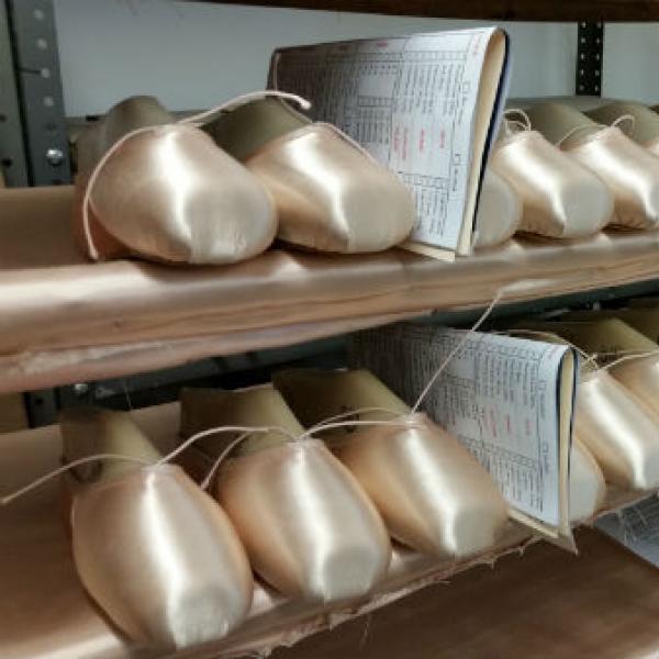 Rows of pink pointe shoes on a shelving unit