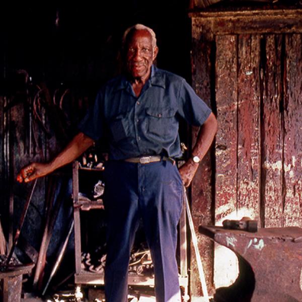 Man standing next to a fire for blacksmithing. 