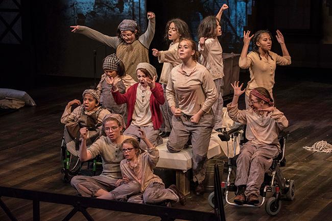 A group of bedraggled children perform as orphans in a production of Annie