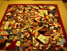 photo of a multi-colored pieced crazy quilt with a red border