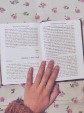 Photo of hand touching Anne Frank's book: The Diary of a Young Girl