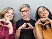 three women who are making hearts with their hands