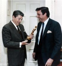 President Ronald Reagan holds an Oscar statuette while Frank Hodsoll looks on