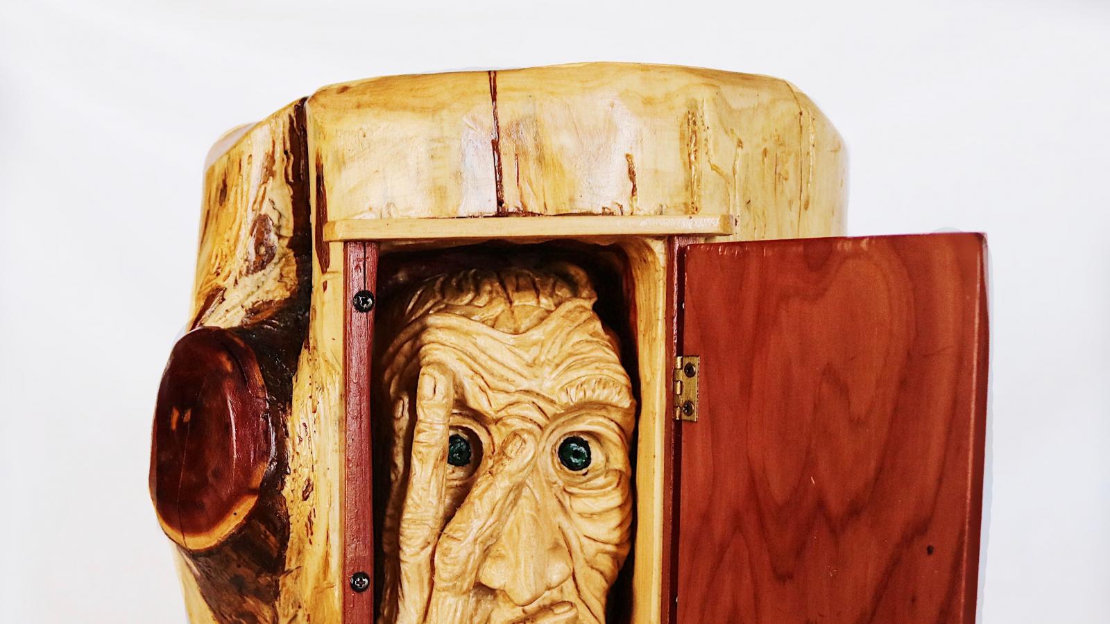 wood carving of a wrinkled face inside a log