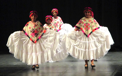 Four young girls in folkloric costumes on stage dancing